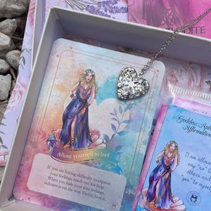 May include: A set of affirmation cards featuring a watercolor illustration of a woman in a blue dress and a silver heart locket necklace. The cards have text that reads "Allow yourself to feel" and "I am allowed to say "no" to others and "yes" to myself".