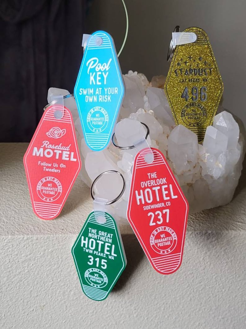 Puede incluir: Cinco llaveros coloridos con forma de llaves de habitaci&oacute;n de motel. Cada llavero tiene un nombre de hotel y un n&uacute;mero de habitaci&oacute;n diferentes. Los llaveros son de pl&aacute;stico y tienen un acabado brillante.