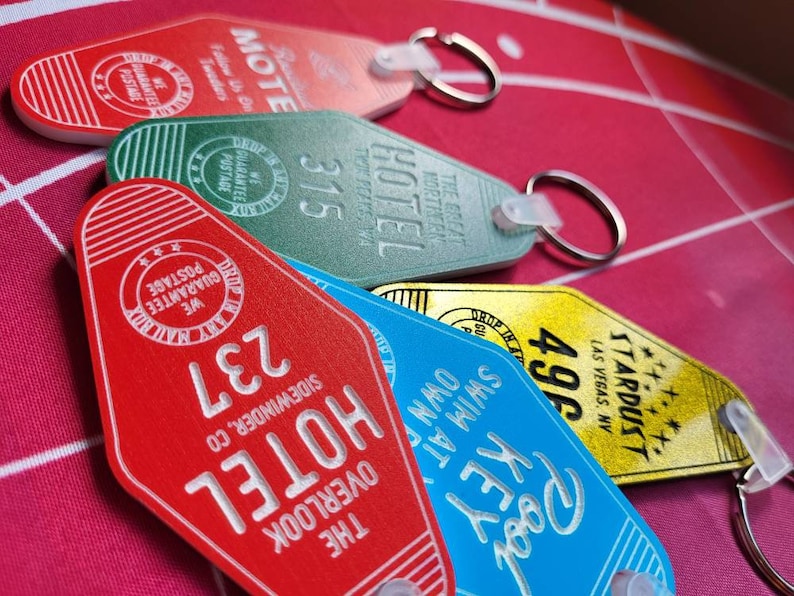 Puede incluir: Una colecci&oacute;n de seis llaveros de motel de estilo vintage. Los llaveros son rojos, verdes, azules, amarillos y blancos. Cada llavero presenta un nombre de motel y un n&uacute;mero de habitaci&oacute;n diferentes. Los llaveros est&aacute;n hechos de metal y pl&aacute;stico.