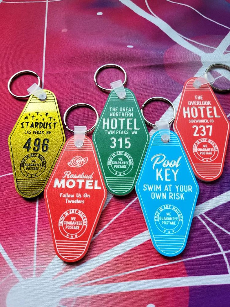 Puede incluir: Un conjunto de seis llaveros con forma de tarjetas de llave de motel vintage. Los llaveros son de varios colores, incluyendo rojo, azul, verde y amarillo. Cada llavero presenta un nombre de hotel y una ubicaci&oacute;n diferentes, como "Stardust Las Vegas, NV", "The Great Northern Hotel Twin Peaks, WA", "Rosebud Motel", "The Overlook Hotel Sidewinder, CO" y "Pool Key".