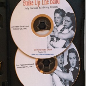 Pode incluir: Dois CDs de &aacute;udio em uma caixa preta. Os CDs apresentam Judy Garland e Mickey Rooney com o texto "Strike Up The Band". Os CDs est&atilde;o rotulados como "Lux Radio Broadcast" com datas de 28 de outubro de 1940 e 17 de novembro de 1941. Os CDs est&atilde;o rotulados como "Old Time Radio Shows Audio CD."
