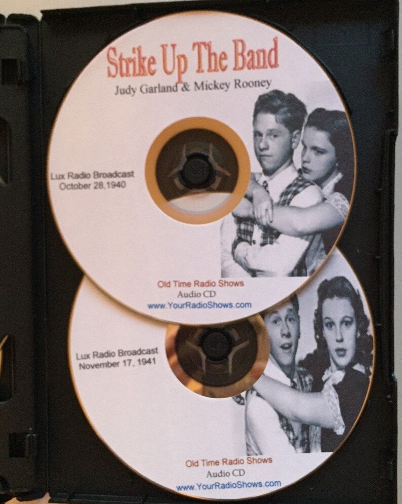 Pode incluir: Dois CDs de &aacute;udio em uma caixa preta. Os CDs apresentam Judy Garland e Mickey Rooney com o texto "Strike Up The Band". Os CDs est&atilde;o rotulados como "Lux Radio Broadcast" com datas de 28 de outubro de 1940 e 17 de novembro de 1941. Os CDs est&atilde;o rotulados como "Old Time Radio Shows Audio CD."