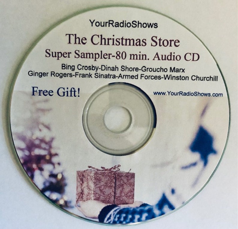 May include: A silver audio CD with the text "The Christmas Store" and "Super Sampler - 80 min. Audio CD." The disc features a festive design with a gift box and the words "Free Gift!" and "YourRadioShows.com."