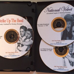 May include: A black CD case containing three audio CDs. The CDs feature images of Judy Garland and Mickey Rooney, and Elizabeth Taylor and Mickey Rooney. The CDs are labeled "Strike Up The Band" and "National Velvet". The CDs are labeled "Old Time Radio Shows".