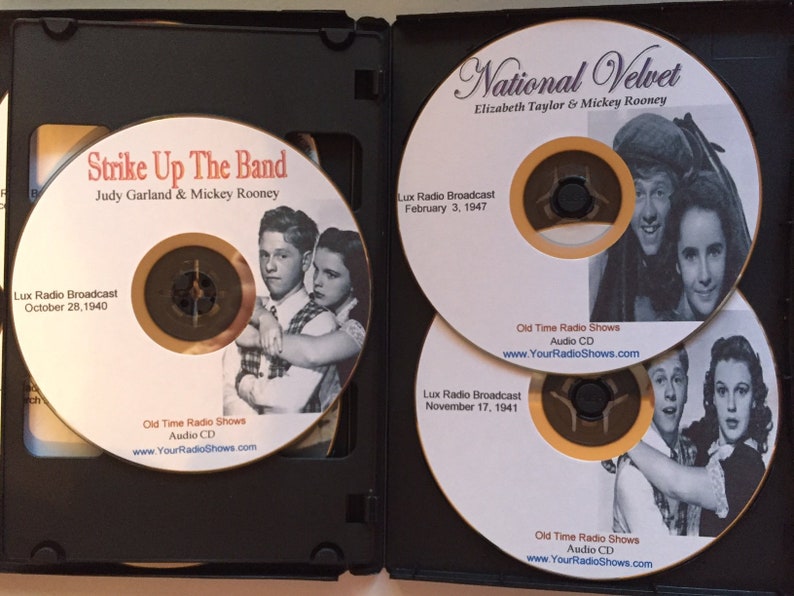 May include: A black CD case containing three audio CDs. The CDs feature images of Judy Garland and Mickey Rooney, and Elizabeth Taylor and Mickey Rooney. The CDs are labeled "Strike Up The Band" and "National Velvet". The CDs are labeled "Old Time Radio Shows".