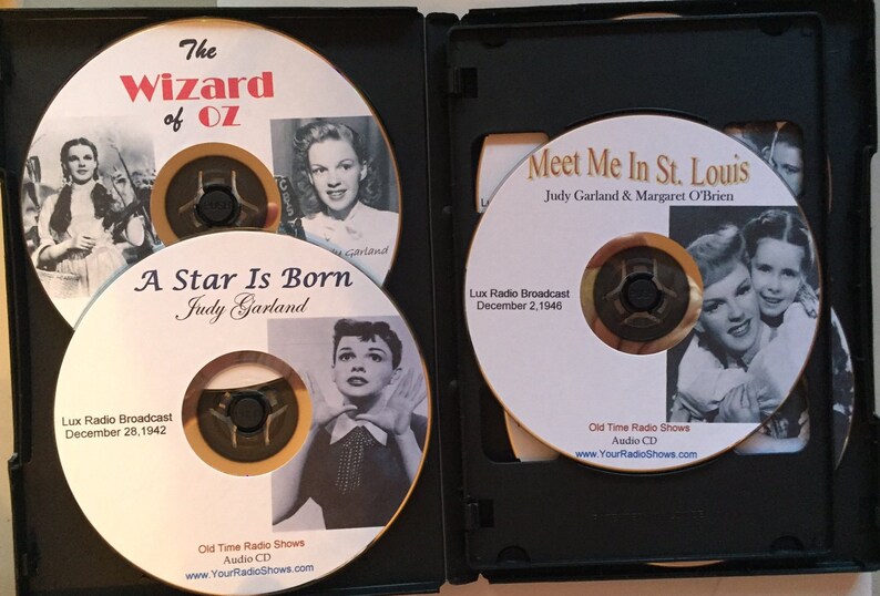 Pode incluir: Uma caixa preta contendo quatro CDs de &aacute;udio com Judy Garland. Os CDs incluem t&iacute;tulos como "O M&aacute;gico de Oz", "Nasce uma Estrela" e "Meet Me in St. Louis". Cada CD tem uma foto vintage de Judy Garland e a data da transmiss&atilde;o.