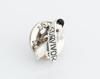 May include: Silver pin in the shape of a ribbon with the word "SURVIVOR" engraved on it.