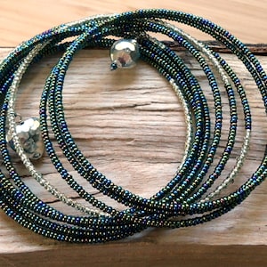 May include: A multi-strand beaded bracelet with silver charms. The bracelet is made of dark green and silver beads.