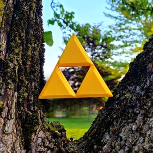 May include: A yellow triangular symbol with a smaller triangle inside, hanging from a tree branch.