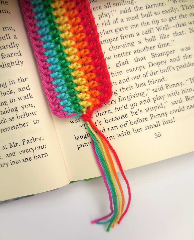 Puede incluir: Un marcap&aacute;ginas de ganchillo arco&iacute;ris con un borla. El marcap&aacute;ginas est&aacute; hecho con hilo de diferentes colores, incluyendo rojo, naranja, amarillo, verde, azul, a&ntilde;il y violeta. La borla est&aacute; hecha con los mismos colores de hilo.