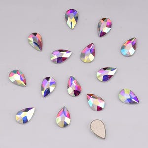 Puede incluir: Surtido de piedras de imitación de cristal en forma de lágrima iridiscente en varios tonos de rosa y morado.