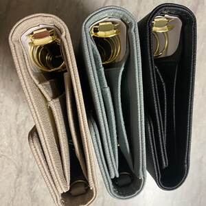Pode incluir: Tr&ecirc;s di&aacute;rios encadernados em couro nas cores bege, cinza e preto com argolas douradas. Os di&aacute;rios est&atilde;o fechados e empilhados um em cima do outro.