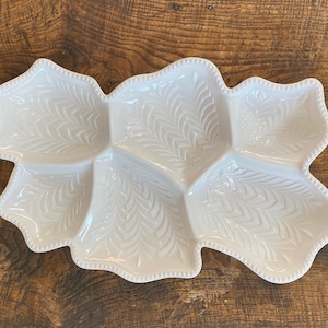 May include: White ceramic serving dish with a leaf design and four sections. The dish has a scalloped edge and a beaded trim.