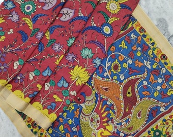 Könnte beinhalten: Ein roter, blauer, gelber und grüner Seiden-Sari mit einem Pfauenmuster. Der Sari hat einen cremefarbenen Rand mit einem Blumendesign. Der Sari ist mit "PK02" gekennzeichnet.