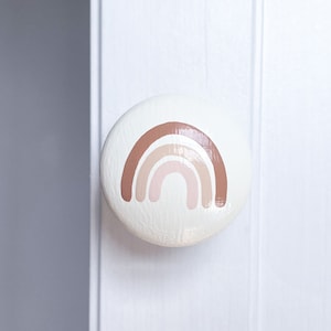 May include: A white round door knob with a brown, pink and beige rainbow design.