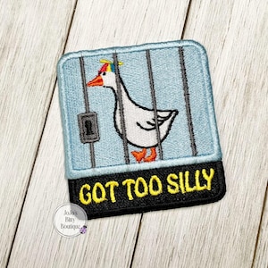 May include: A blue and white embroidered patch with a goose in a cage and the text "Got Too Silly".