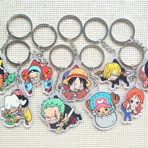 May include: A set of 10 colourful anime character keyrings featuring characters from the popular anime series One Piece. The keyrings are made of clear acrylic and feature various characters including Luffy, Zoro, Chopper, and Nami.