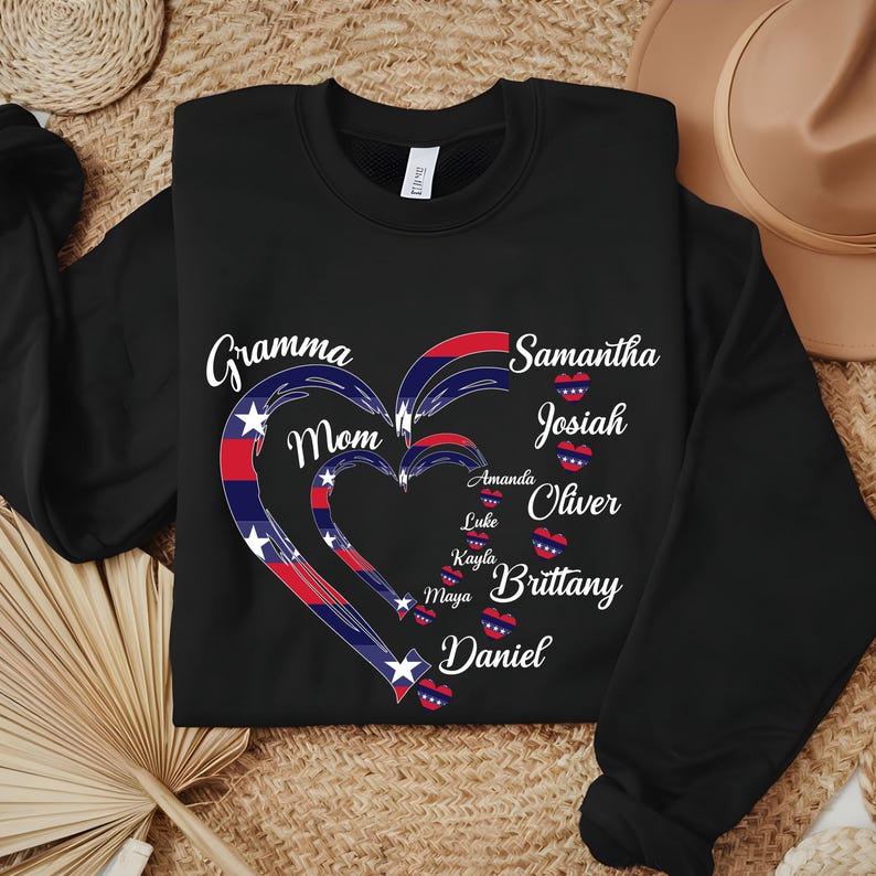 K&ouml;nnte beinhalten: Schwarzes Sweatshirt mit einem Herzdesign in Rot, Wei&szlig; und Blau. Das Herz besteht aus drei ineinander verschachtelten Herzen mit Namen wie "Gramma", "Mom", "Samantha" und "Josiah" in wei&szlig;er Schrift. Ein personalisiertes, gem&uuml;tliches Geschenk.