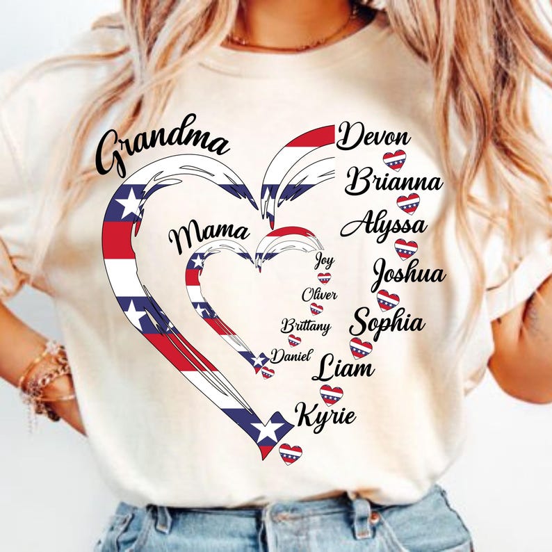 K&ouml;nnte beinhalten: Cremefarbenes T-Shirt mit herzf&ouml;rmigem Design in Rot, Wei&szlig; und Blau. Die W&ouml;rter "Grandma" und "Mama" sind abgebildet, zusammen mit Namen wie Devon und Brianna. Das Design hat ein patriotisches Thema.