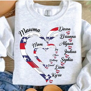 K&ouml;nnte beinhalten: Ein hellgraues Sweatshirt mit einem Herzdesign in Rot, Wei&szlig; und Blau. Das Design enth&auml;lt die W&ouml;rter "Mawma" und "Mom" sowie Namen wie Devon, Brianna und Joshua. Das Sweatshirt ist von der Marke Gildan.