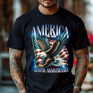 May include: Black t-shirt featuring a graphic of an American flag and a bald eagle. The text "AMERICA 1776-2026 250TH ANNIVERSARY" is displayed above and below the eagle and flag design. The eagle is holding the flag.