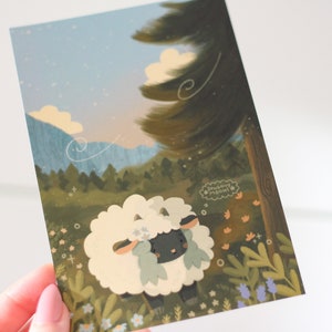 Pu&ograve; includere: Una pecora bianca con la faccia nera e fiori blu nella sua lana sta in piedi in un campo di erba verde e fiori. La pecora sta guardando in alto verso un alto albero verde con un cielo blu e nuvole bianche sullo sfondo. Il testo "Dreamy Moments" &egrave; scritto in una nuvola di dialogo sopra la pecora.