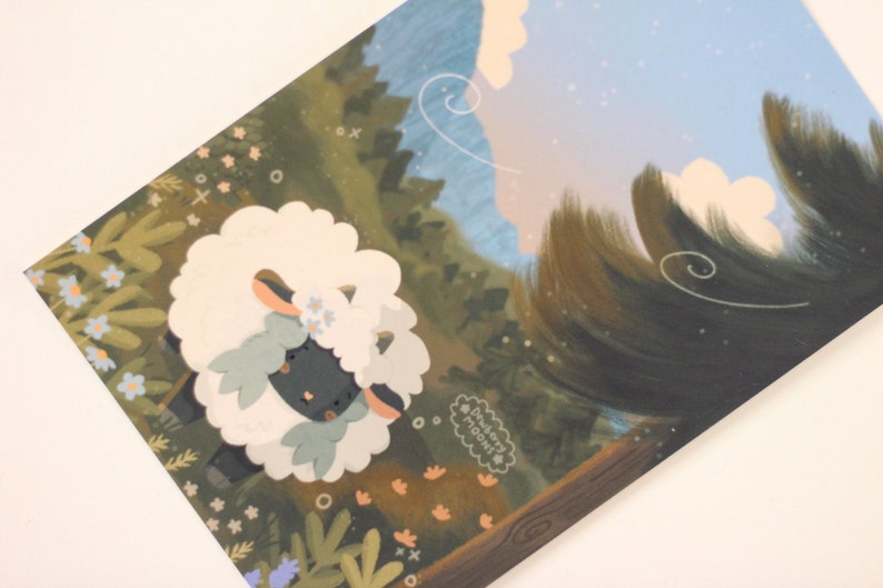 Pu&ograve; includere: Una pecora nera con un mantello bianco e soffice e fiori blu nei capelli si trova in una foresta verde con un cielo blu e nuvole bianche sullo sfondo. Il testo "dreamy moodi" &egrave; scritto in un cerchio bianco.