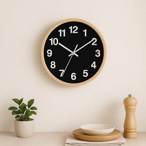May include: A black and white clock with a wooden frame, a small potted plant, a white bowl on a wooden stand, and a wooden salt and pepper shaker on a light brown countertop.