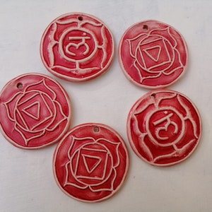 May include: Five red ceramic round ornaments with white symbols and designs. Each ornament has a different symbol, including a triangle, a square, and a circle. The ornaments are about 2 inches in diameter.