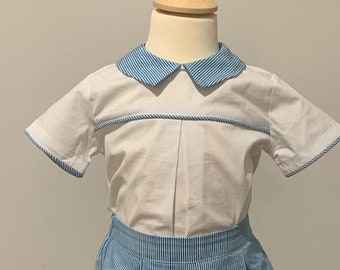 May include: A white short-sleeved button-up shirt with a blue and white striped collar and a blue and white striped pair of shorts.