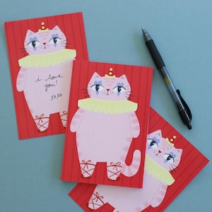 May include: Three rectangular greeting cards featuring a pink cat illustration on a red striped background. The cat wears a yellow ruffled collar, a small party hat, and ballet slippers. One card includes the handwritten text I love you! XOXO.