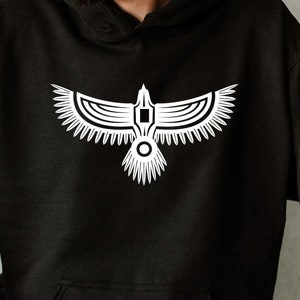 May include: A black hoodie with a white stylized eagle design on the front. The eagle has a geometric pattern and is facing forward with its wings spread.