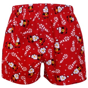 May include: Red boxer shorts featuring a repeating pattern of Santa Claus faces and candy canes. The shorts have a button closure and an elasticated waistband. A festive design for the holiday season.