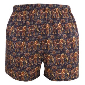 May include: Boxer shorts featuring a repeating pattern of detailed elephants in brown, gold, and orange on a dark blue fabric. The shorts have an elasticated waistband.