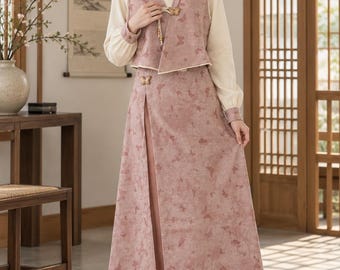 May include: A dusty rose vest and matching long skirt set featuring a subtle butterfly pattern, worn over a cream-colored long-sleeve blouse. The vest has a butterfly-shaped toggle closure, and the skirt includes a high side slit and fringe trim.