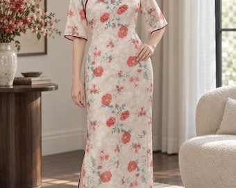 May include: A floor-length cheongsam dress in a light beige fabric featuring a red floral pattern. The garment has a mandarin collar, elbow-length sleeves with dark red trim, a side slit, and a diagonal button closure with dark red fabric knots.