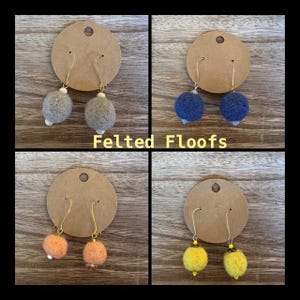 May include: Four pairs of felt ball earrings displayed on brown card stock. The earrings are in gray, blue, orange, and yellow.