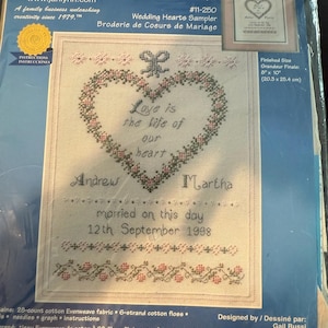 May include: A Janlynn counted cross stitch kit, Wedding Hearts Sampler, featuring a heart design with the text "Love is the life of our heart." Includes names "Andrew" and "Martha" and the date "12th September 1998." Finished size is 8" x 10".