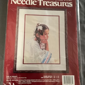 May include: A sealed package for a Colorart Cross Stitch kit titled "Needle Treasures." The kit features a framed portrait of a young person in traditional attire, with the text "Lost in Thought." The frame size is 14" x 18", and the image size without the mat is 10" x 14".