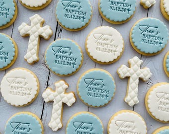 Può includere: Una collezione di biscotti di zucchero decorati con glassa blu e bianca. I biscotti presentano un design a croce e il testo "Theo's Baptism 01.12.24+".
