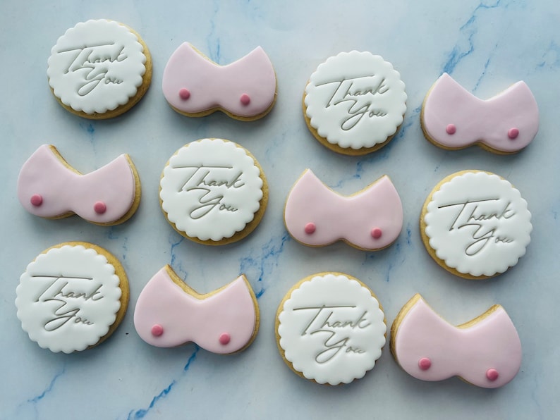 May include: Assortment of decorated cookies with pink icing and the text "Thank You" in white icing.
