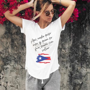 May include: White t-shirt with a black and white graphic of the Puerto Rican flag and the text "Aqui, nadie quiso irse, y quien se fue, sueña con volver".