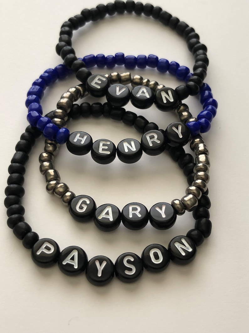 Pu&ograve; includere: Cinque braccialetti neri con perline e lettere bianche che compongono i nomi Evan, Henry, Gary e Payson.