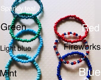 May include: A set of ten beaded bracelets in various colors, including teal, green, light blue, mint, red, and blue. Some bracelets have names spelled out on them, including "Cody" and "Blythe".