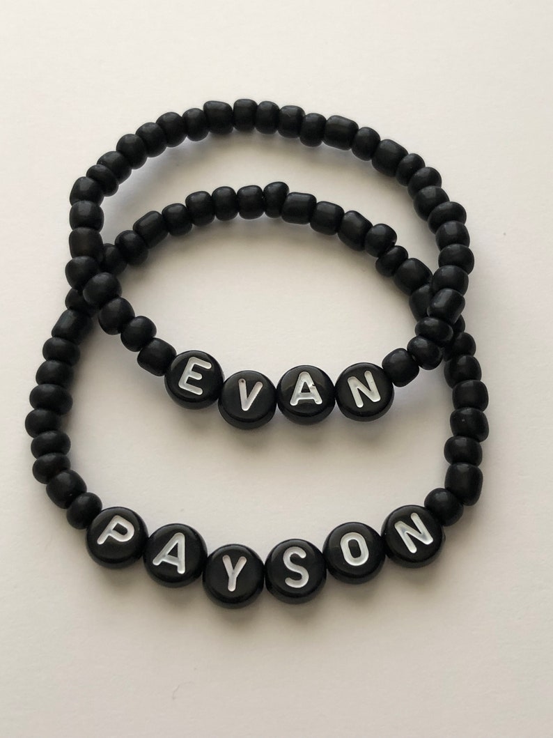 Pu&ograve; includere: Due braccialetti neri con perline con i nomi "Evan" e "Payson" scritti in lettere bianche.