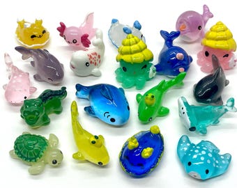 May include: A collection of colorful, miniature sea creatures. The assortment includes dolphins, axolotls, turtles, and stingrays in various colors like blue, green, pink, and yellow. Each figurine has a glossy finish.