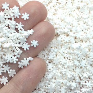 May include: White snowflake sprinkles for crafts and baking. The sprinkles are small and have a 3D snowflake shape.
