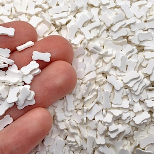 May include: White bone-shaped sprinkles for baking and decorating. The sprinkles are small and scattered in a pile.