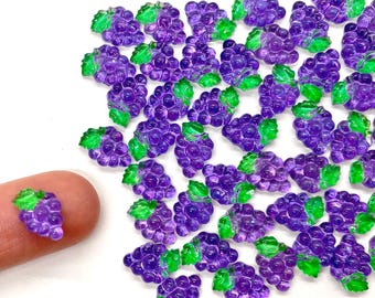 May include: A large quantity of purple and green grape charms. The charms are made of plastic and have a glossy finish. They are perfect for adding a touch of whimsy to crafts and jewelry.