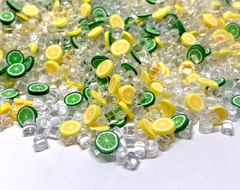 May include: A close-up of a pile of clear plastic ice cubes with yellow lemon and green lime slices scattered throughout.